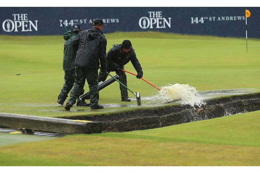 Staff push water into the burn after heavy rainfall prior to the second round of the 144th Open Championship at The Old Course