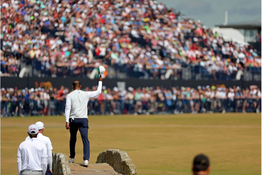 Tiger Woods doffs his cap to the crowd as he crosses the Swilken Bridge during his walk down the 18th hole at the end of his second round at the 150th Open Championship.