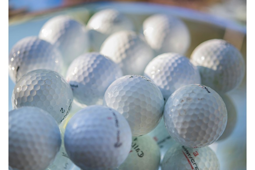 A bucket of golf balls of different makes.