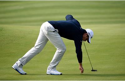 Justin Rose repairs a pitch mark