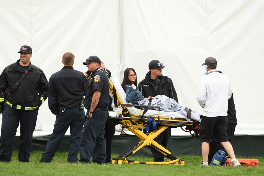 spectators sitting on stretcher after being hit by golf cart