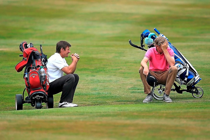 A pair of golfers sit and wait to play their next shot.